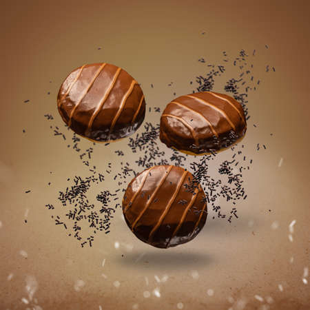 Flying doughnuts with chocolate glaze and salted caramel stripes on brown background