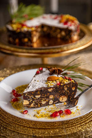 Slice of raw vegan chocolate cake with pistachio, almond and nuts for Christmas tableの写真素材