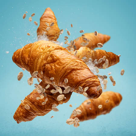 Freshly baked croissant flying in air on blue backgroundの写真素材