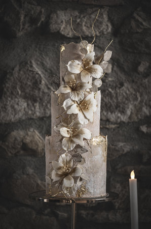 Wedding cake with flowers on gray stone wall background