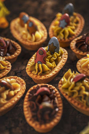Small tartlet pastries with different cream decorated with chocolate eggsの写真素材
