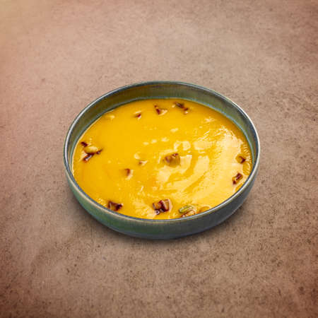 Bowl of tasty carrot cream soup on brown backgroundの写真素材