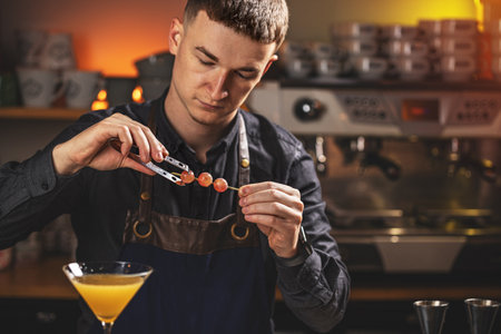 Portrait of barman adding decor elements to martini glass
