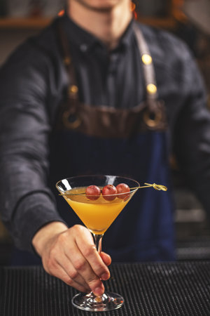 Bartender serving a yellow martini in bar