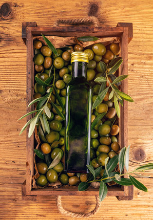 Green ripe olives in wooden crate and freshly pressed olive oil in bottleの写真素材