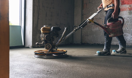 Worker performing and polishing sand and cement screed floor on the construction siteの写真素材