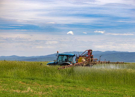 Spraying machine working on the green oat field