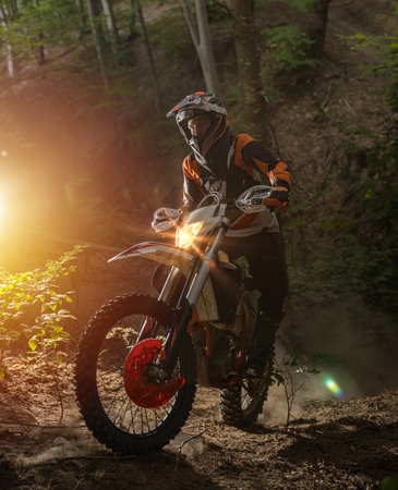 Motorcyclist on a sport motorcycle rides through a difficult forest areaの写真素材
