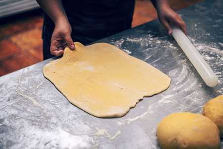 Woman's hands roll the dough in professional kitchen counter
