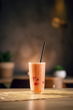 Refreshing and healthy smoothie made with red berries and a straw is placed on a table in a cafeの写真素材