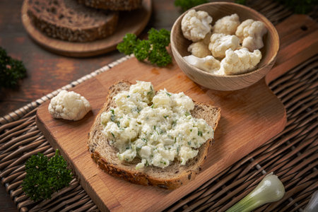 Delicious cauliflower salad with fresh herbs being spread on a slice of breadの写真素材