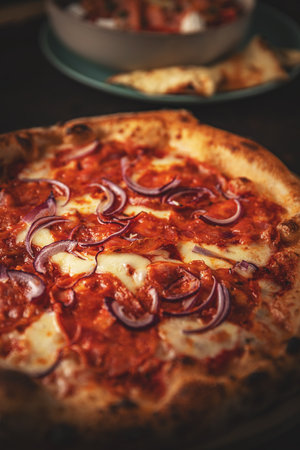 Delicious pizza with pepperoni, red onions, and melted mozzarella, close upの写真素材