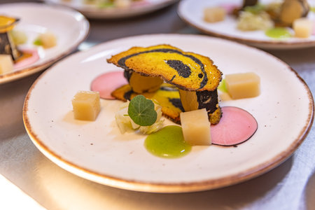 Small gourmet appetizer with colorful ingredients is being prepared on a white plate in a restaurant...