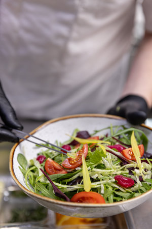Professional chef adding final touches to a vibrant salad, close upの写真素材