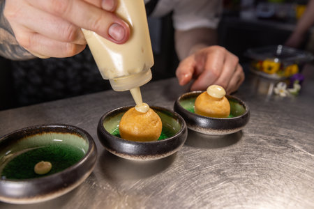 Chef garnishing small round appetizers with cream fillingの写真素材