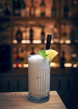 Refreshing pina colada cocktail standing on bar counter with blurry back bar