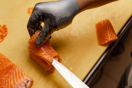 Chef arranging slices of fresh salmon on cutting boardの写真素材