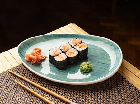 Hosomaki rolls with salmon, pickled ginger, and wasabi on elegant plate, ready to eatの写真素材