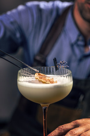 Bartender garnishing cocktail with dried orange and lavenderの写真素材