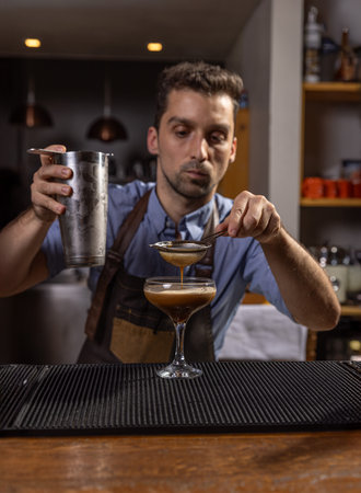 Bartender carefully pouring an ingredient into a cocktail glassの写真素材