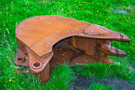 Old rusty excavator shovel in the grass