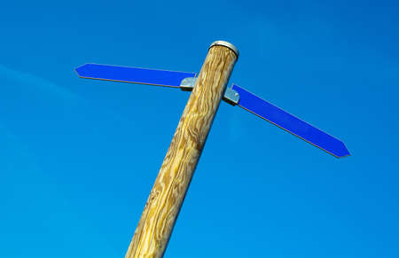 Wooden pole with two blue direction arrowsの写真素材