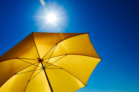 Yellow Umbrella with Bright Sun and Blue Skyの写真素材