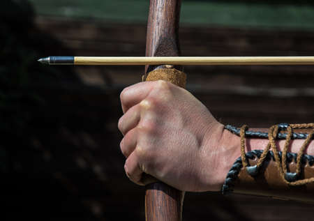 Hand of an archer holds bow and arrow and aims at targetの写真素材
