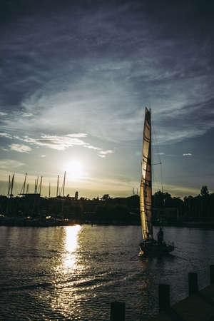 Sailboat in Front of Sun in Harborの写真素材