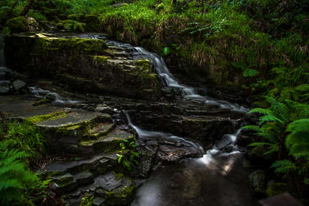 Small Long Exposured Creek With Waterfall In Mystic Forest Near Ullapool In Scotland