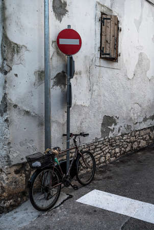 Old Bicycle Locked With Chain On Pole In Front Of Old Houseの写真素材