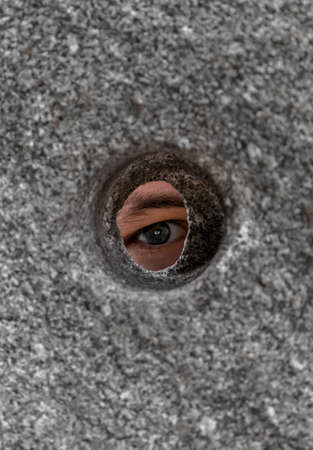 Open Eye Looking Through Round Hole In Stone Wallの写真素材