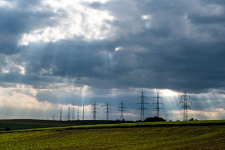 Pylons With High Voltage Energy Wires In Farmland At Stormy Weatherの写真素材