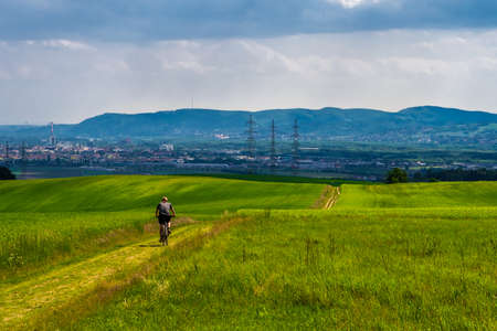 Man Rides Mountainbike In Rural Landscape In Front Of Skyline Of Vienna In Austriaの写真素材