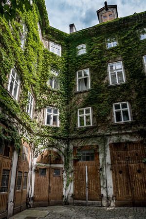 Courtyard Of A HIstoric Building With Wooden Doors And Ivy Overgrown Wallsのeditorial素材