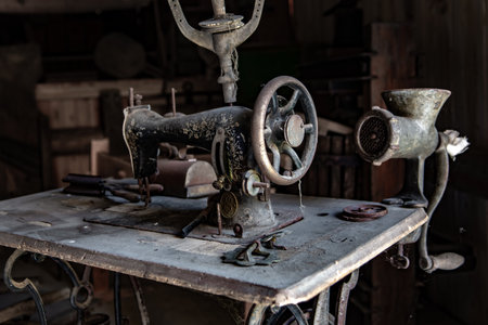 Dusty Vintage Manual Sewing Machine And Kitchen Tools On Table In Old Barnの写真素材