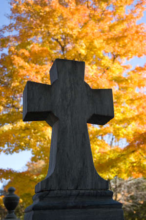 a close up of a cross on a cemetary monument at autumnの写真素材