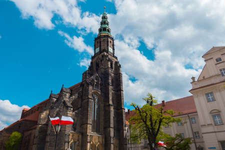 Swidnica Old gothic church rising to the sky. High dark tower and nave completed with bow on blue background and full of clouds of sky.のeditorial素材