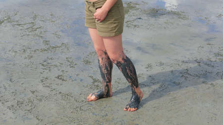 Legs covered with black health mud. Mud has healing properties that rejuvenate the skin and micronutrients help fight many diseases. This is a type of treatment used in many SPA centers.の写真素材