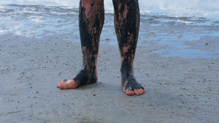 Legs covered with black health mud. Mud has healing properties that rejuvenate the skin and micronutrients help fight many diseases. This is a type of treatment used in many SPA centers.の写真素材