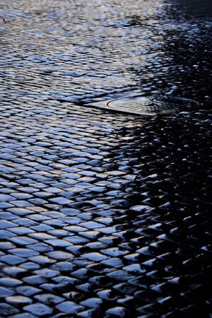 Rain soaked cobbled street with drain cover, Romeの写真素材