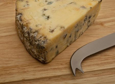 Wedge of Stilton cheese on wooden cheesboard with cheese knifeの写真素材