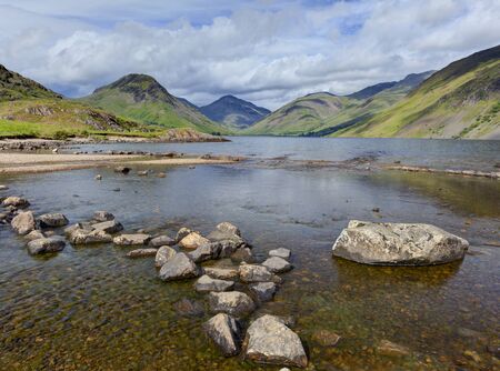 Wastwater looking towards Yewbarrow, Great Gable and Scafell with rocks in waterの写真素材