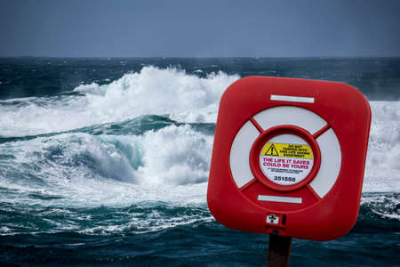 red and white lifebelt against stormy sea and high wavesの写真素材