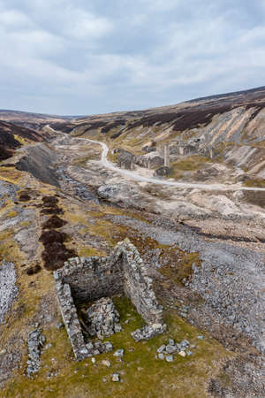 ruins of the old gang lead mine in the hills above reeth in the yorkshire dales from the hillside opposite vertical formatの写真素材