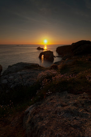 sunset at lands end cornwall with enys dodnan and the armed knight rock formations vert format