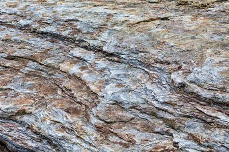 close up of blue and brown weathered and sculpted surface of rock formation by the sea shore at...