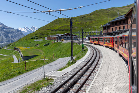 mountain railway train arriving at kleine scheidegg station switzerland sunny summer dayの写真素材