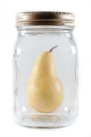 Ripe canning pear behind a glass mason jar on a white isolated background.の写真素材