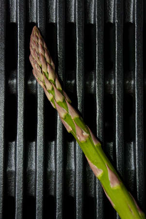 Green stalk of asparagus on black cast iron bbqの写真素材